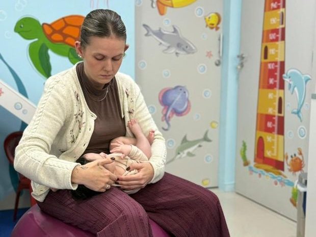 Bebê relaxado no colo da fisioterapeuta durante sessão de massagem Shantala