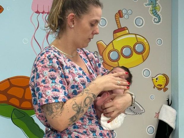 Fisioterapeuta avaliando a mobilidade da cabeça e do pescoço de um recém-nascido no colo