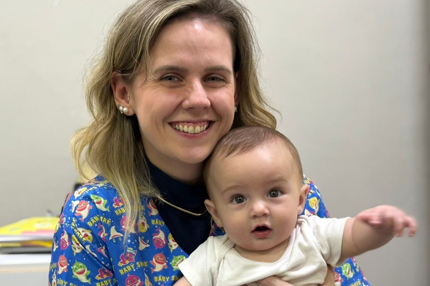 Stephanie Hackradt, fisioterapeuta pediátrica, sorrindo com um bebê no colo no consultório